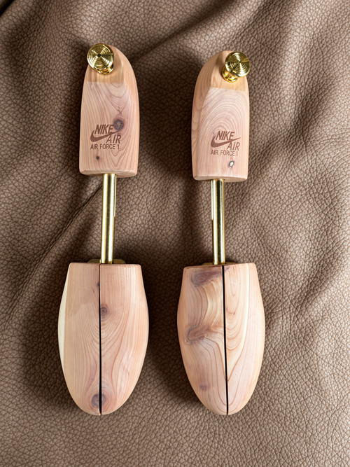 Overhead view of Nike Air Force 1 cedar shoe trees with gold-tone hardware and engraved branding